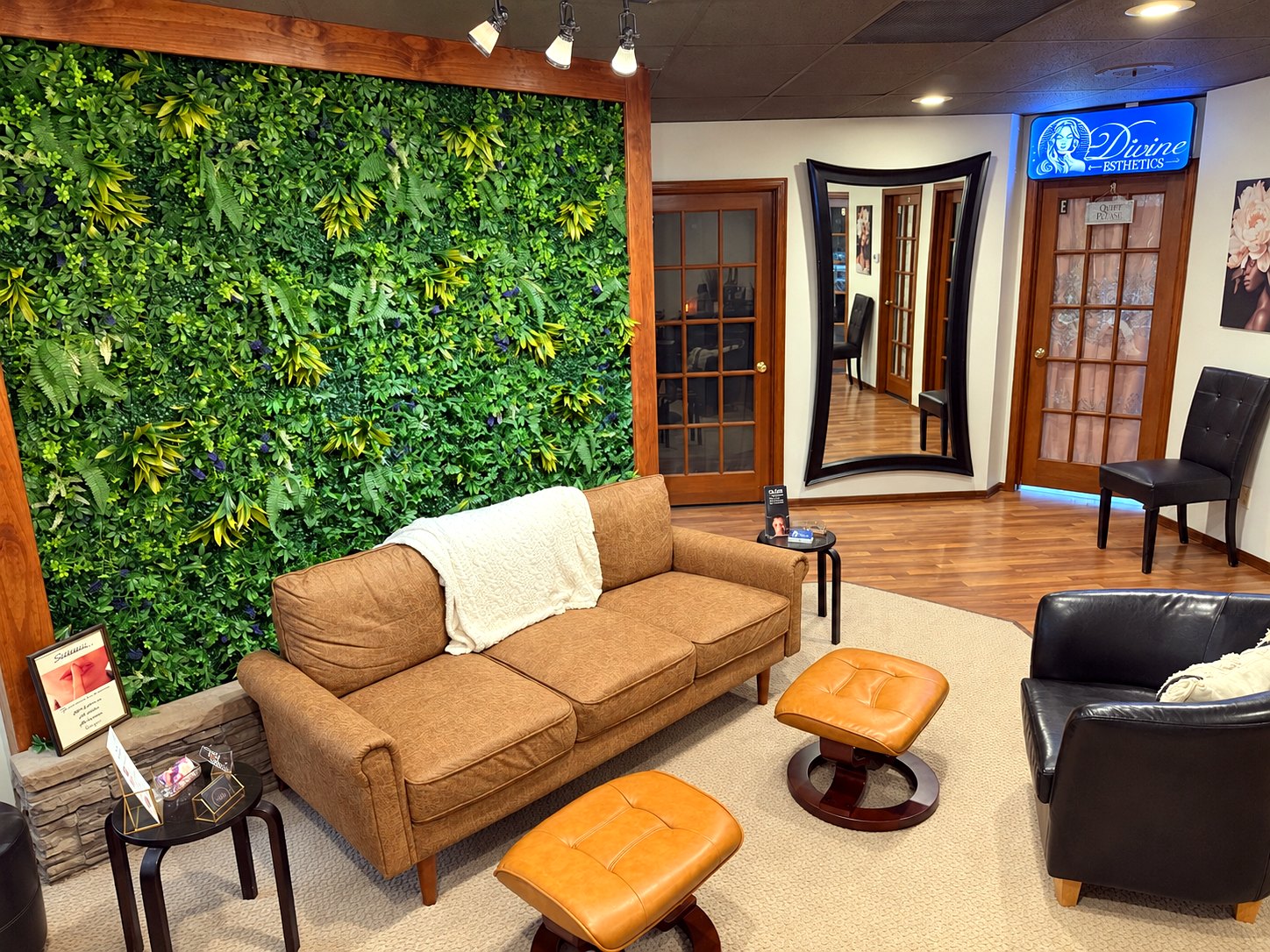 Client lounge at Springs Spa & Salon in Colorado Springs, with a green plant wall, leather sofa and doors to the treatment suites