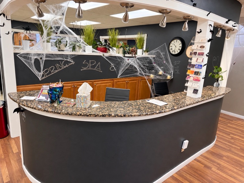 Front desk at Springs Spa & Salon in Colorado Springs, with a curved granite counter and the Springs Spa sign, decorated for Halloween