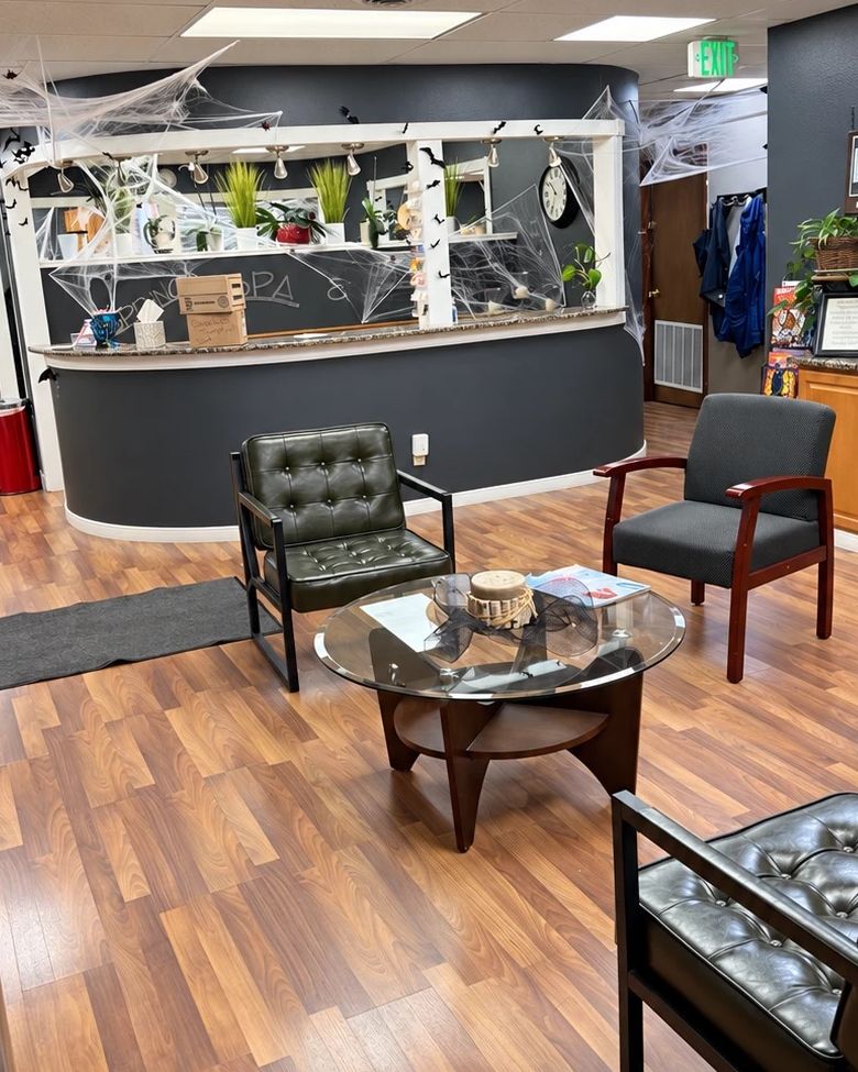 Waiting area with leather chairs, a round glass table and retail shelves in front of the front desk at Springs Spa & Salon