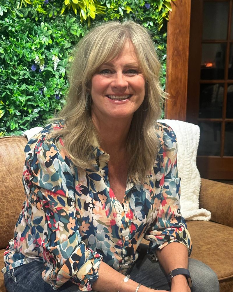 Jill, owner of Springs Spa & Salon & Suites, smiling on the sofa in the salon lounge